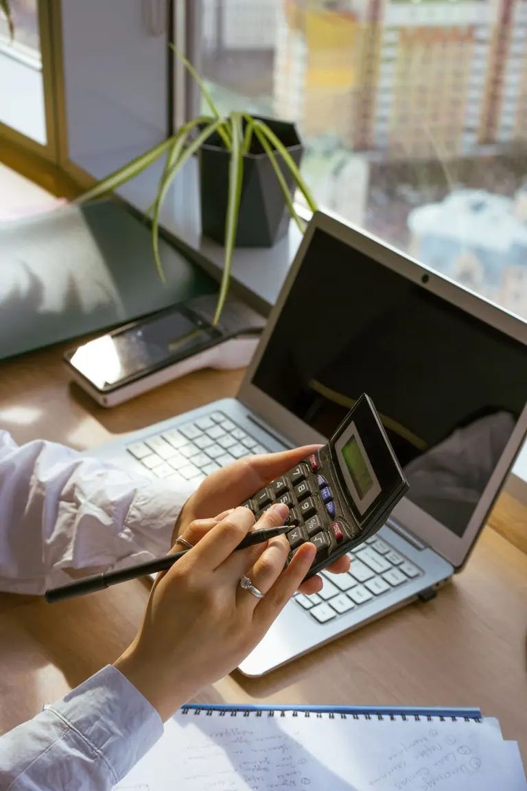 Calculating a budget beside a laptop